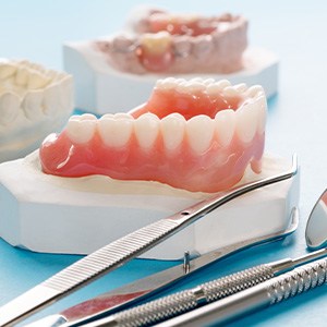 Lower set of full dentures on a cast next to dental instruments