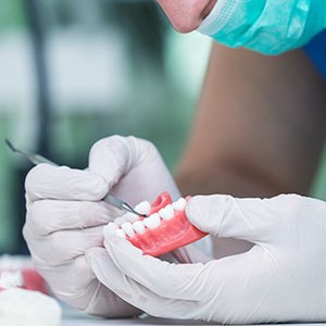 Lab tech in white gloves placing pontics in denture base