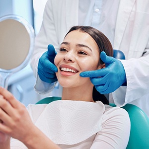 Woman smiling at reflection in handheld mirror