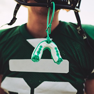 Green and white mouthguard hanging from helmet